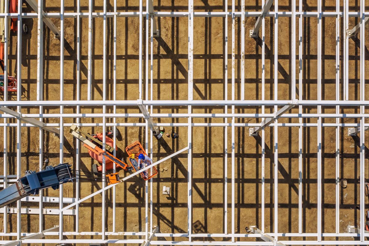 Luchtfoto recht van boven van een staalconstructie in aanbouw met bouwmaterieel