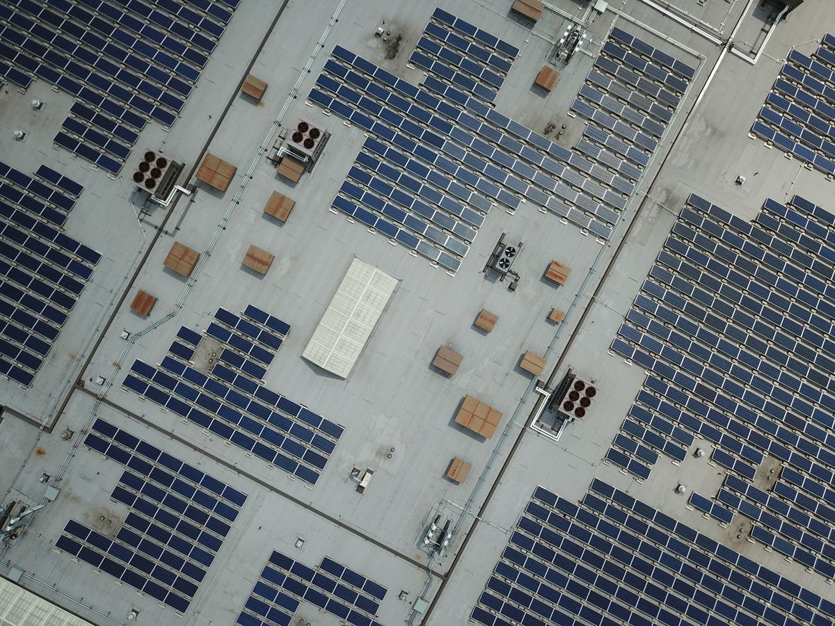 Dronefoto van een plat bedrijfsdak met zonnepanelen en dakdoorvoeren